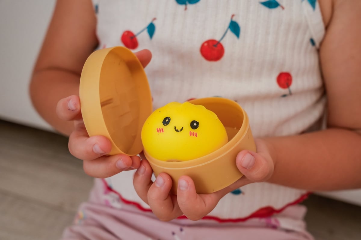 Child holding a bamboo steamer filled with squishy dumpling toys